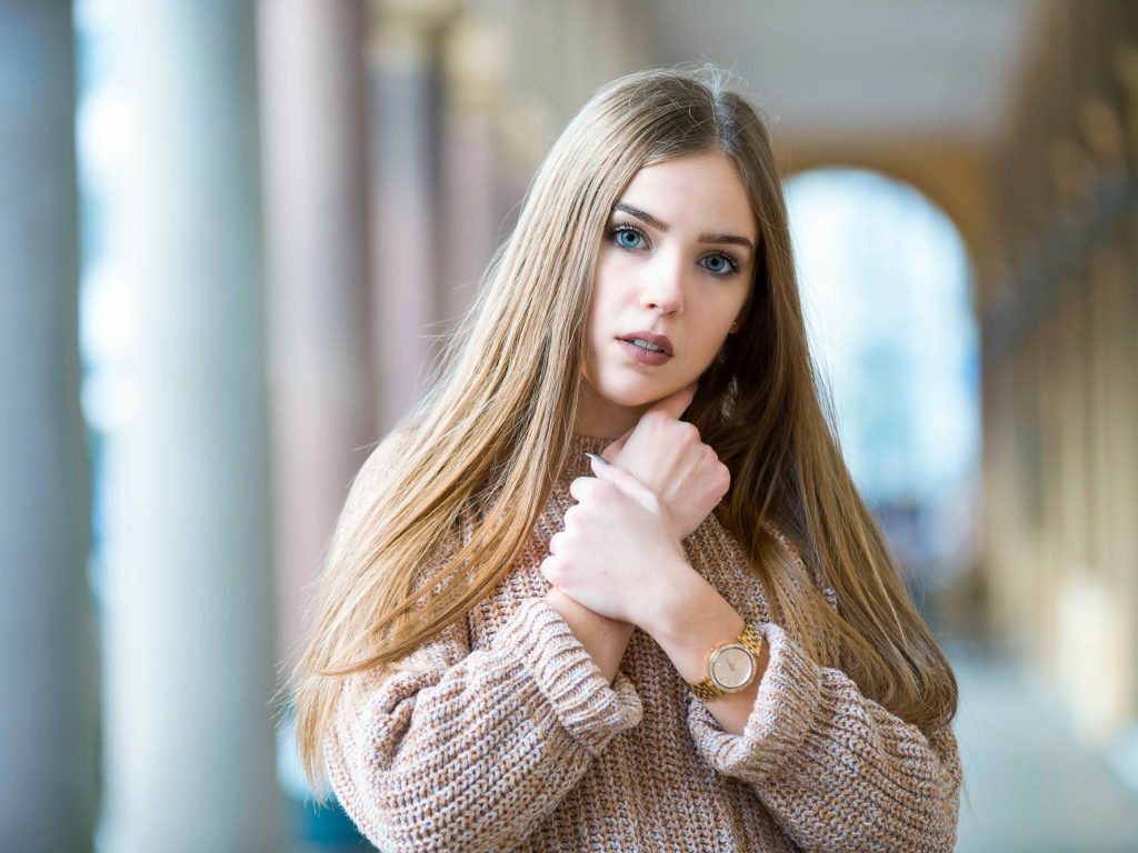 Красивая голубоглазая блондинка в теплом свитере с часами на руке