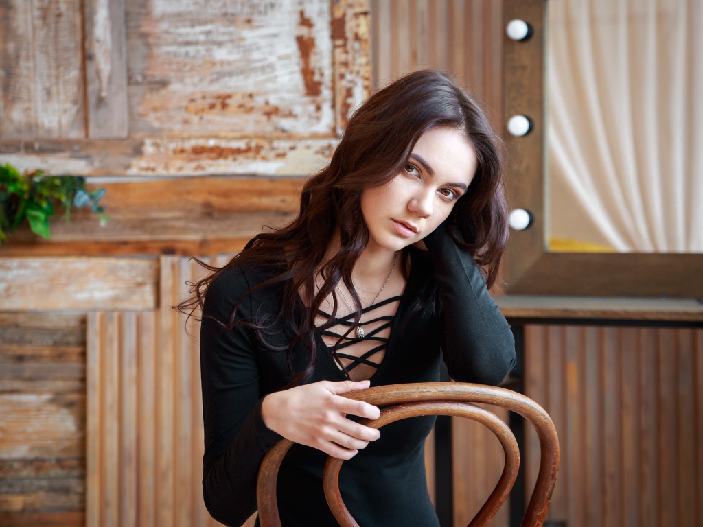 Красивая кареглазая девушка сидит на стуле