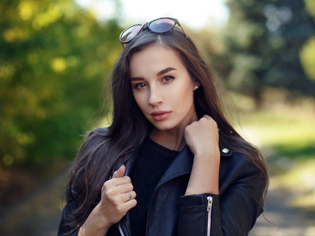 Красивая девушка в черной куртке с очками на голове
