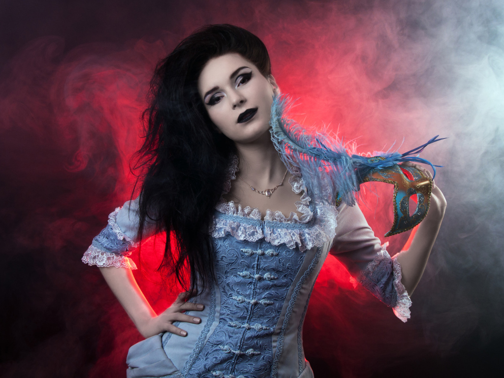 Красивая девушка в старинном платье с маской в руке