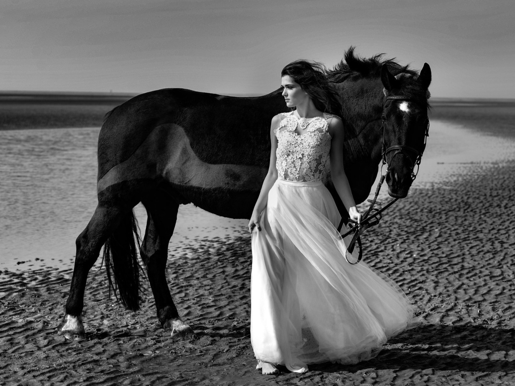 Красивая девушка в свадебном платье с лошадью на берегу моря