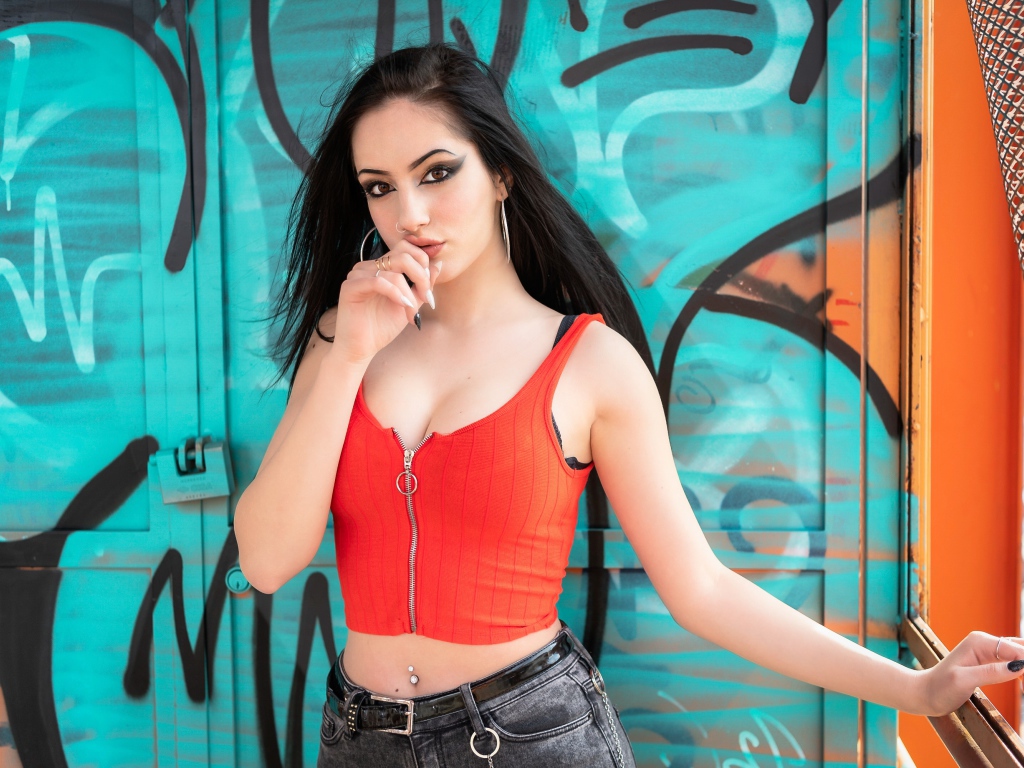 Красивая девушка с пирсингом стоит у стены