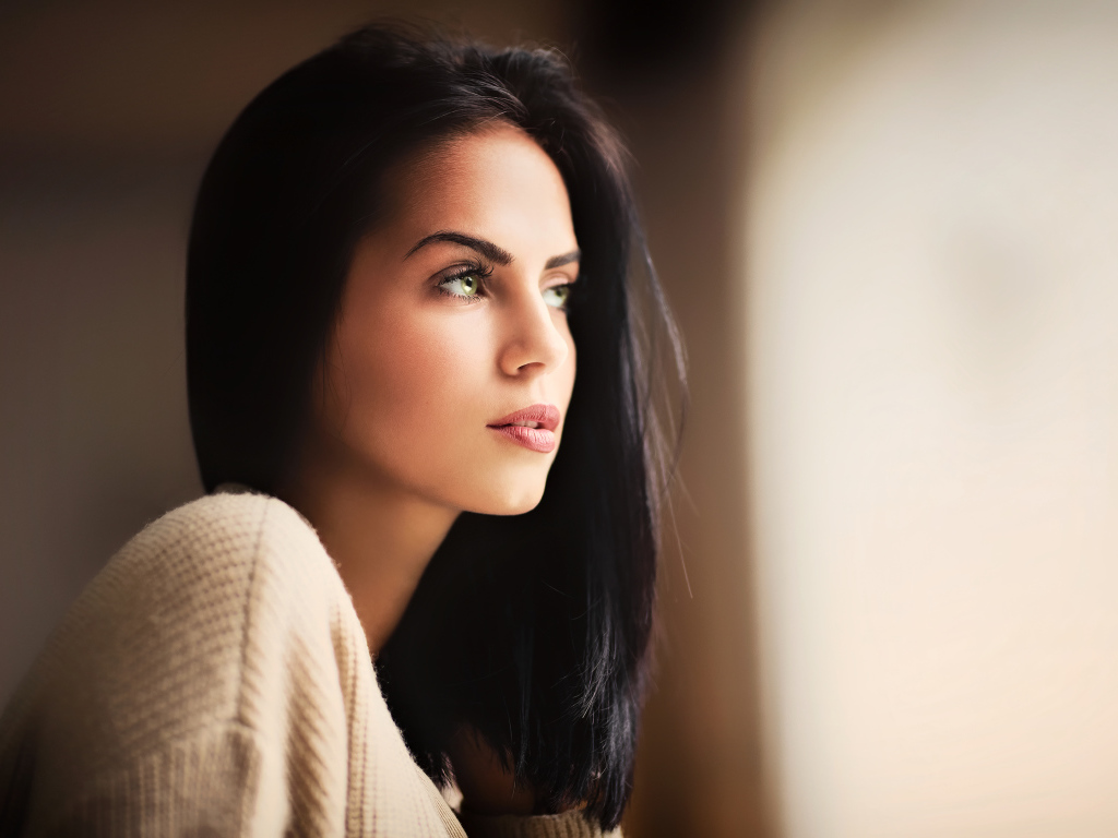 Красивая девушка зеленоглазая смотрит в окно 