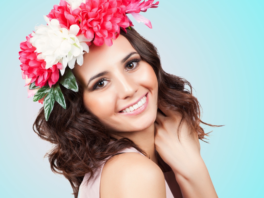 Красивая улыбающаяся девушка с венком на голове на голубом фоне