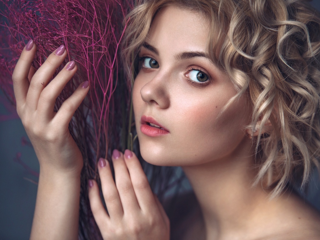 Красивая молодая блондинка с красным растением в руках