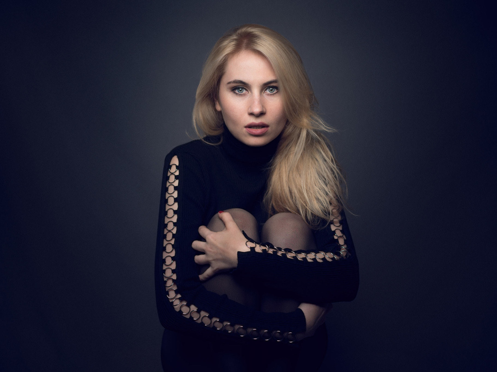 Блондинка в черном наряде на сером фоне