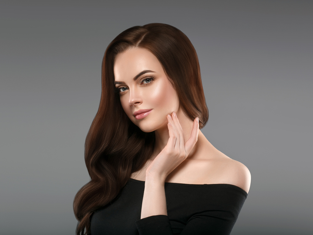 Нежная длинноволосая шатенка в черном платье на сером фоне