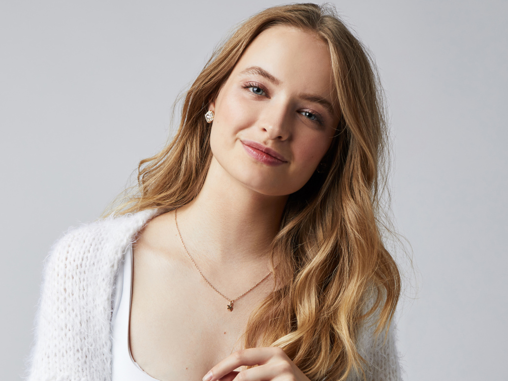 Нежная улыбающаяся голубоглазая девушка на сером фоне