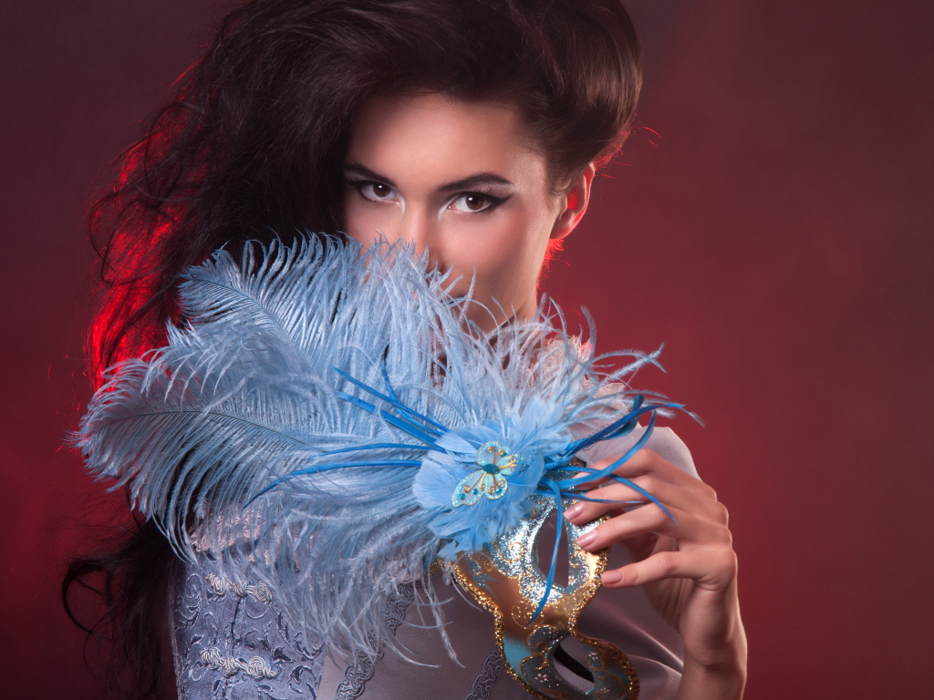 Длинноволосая девушка с маской с перьями в руке