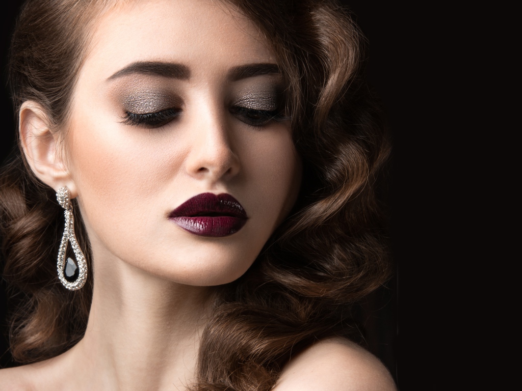 Длинноволосая девушка с ярким макияжем на черном фоне