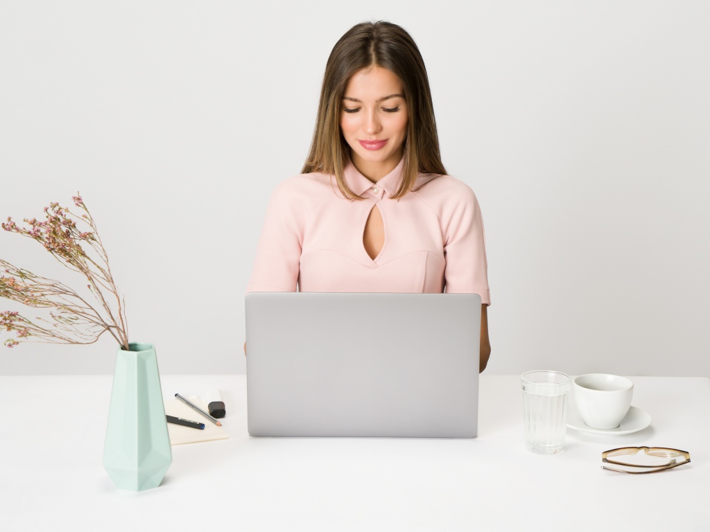 Умная девушка за ноутбуком на сером фоне