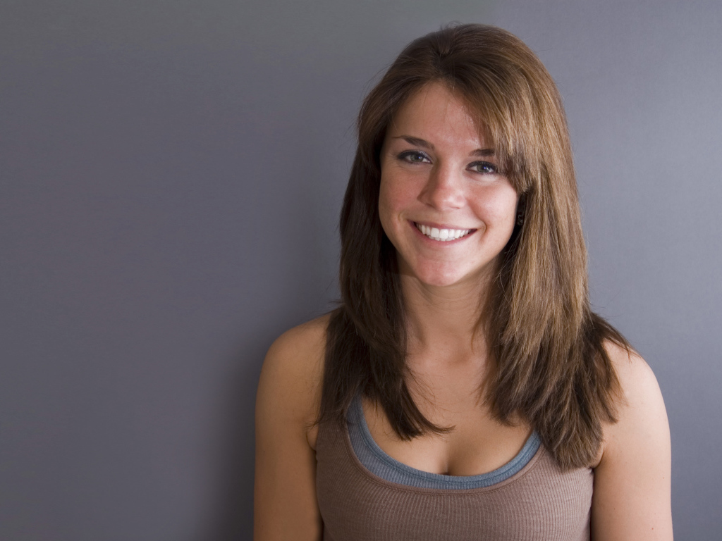 Улыбающаяся милая девушка у серой стены