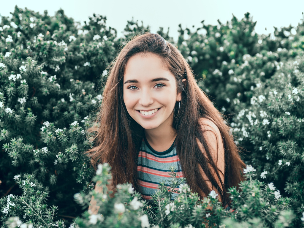 Улыбающаяся девушка сидит в зеленых зарослях 