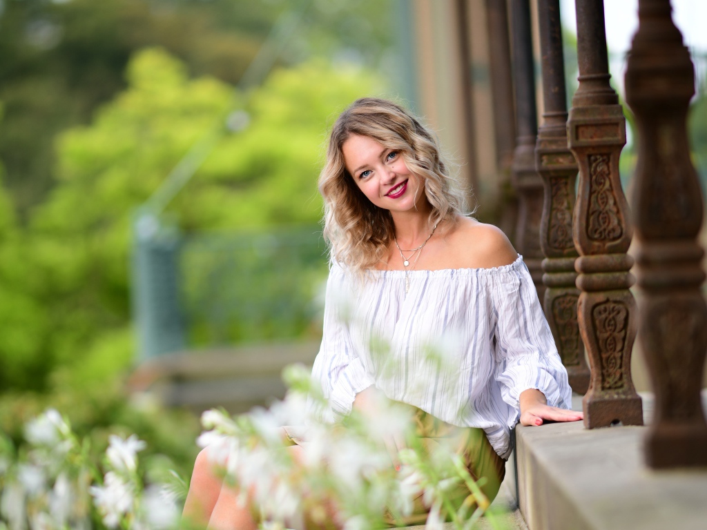 Улыбающаяся девушка сидит на ступенях