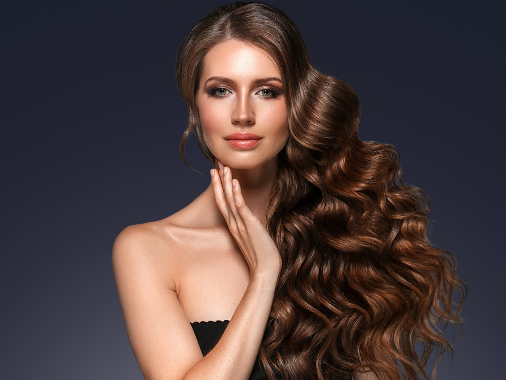 Стильная девушка с красивыми длинными волосами на сером фоне