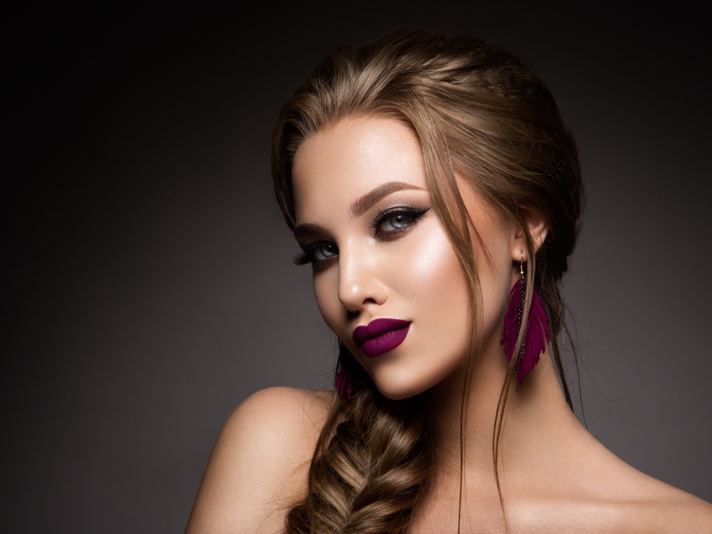 Девушка с ярким макияжем и косой на сером фоне