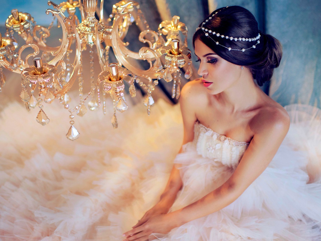Молодая девушка в белом платье у красивой  люстры