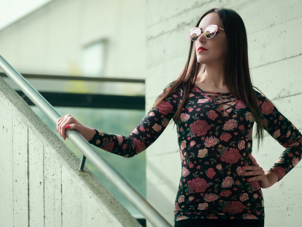 Молодая девушка в солнечных очках стоит на ступеньках