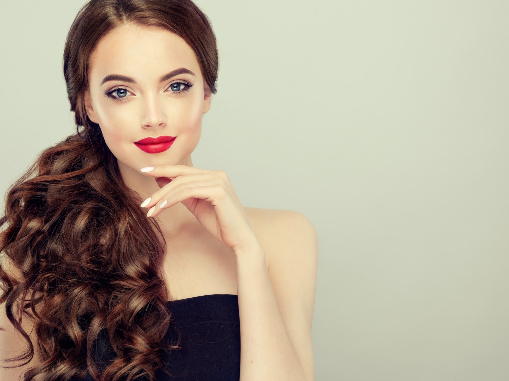 Молодая девушка с красивыми волосами на сером фоне