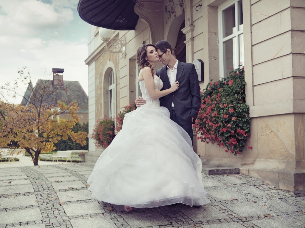 Жених и невеста стоят у здания 