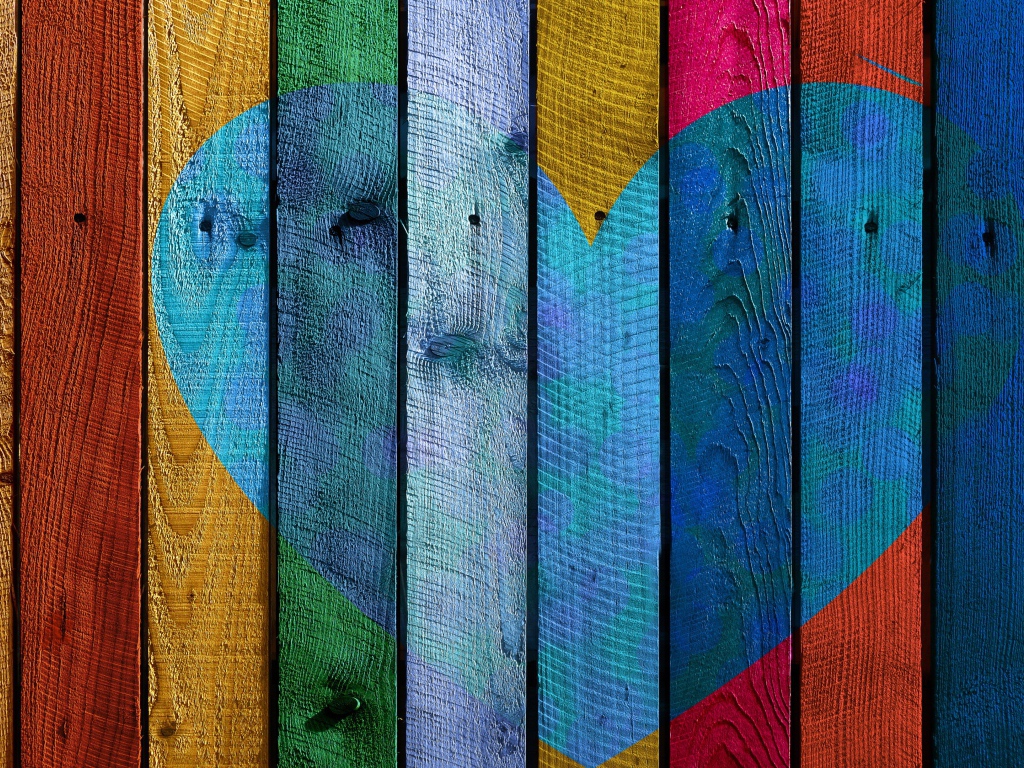 Голубое сердце нарисовано на разноцветном заборе