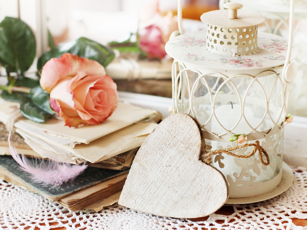 Фонарь со свечей на столе с розой, сердцем и книгами