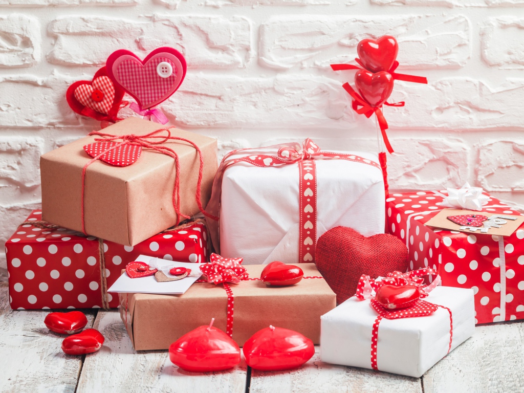 Много  подарочных коробок с сердечками на фоне стены