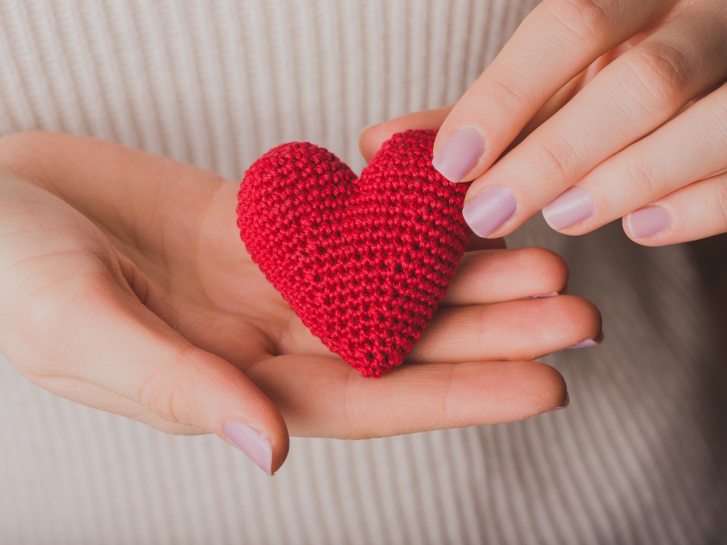 Красное вязаное сердце в руках у девушки