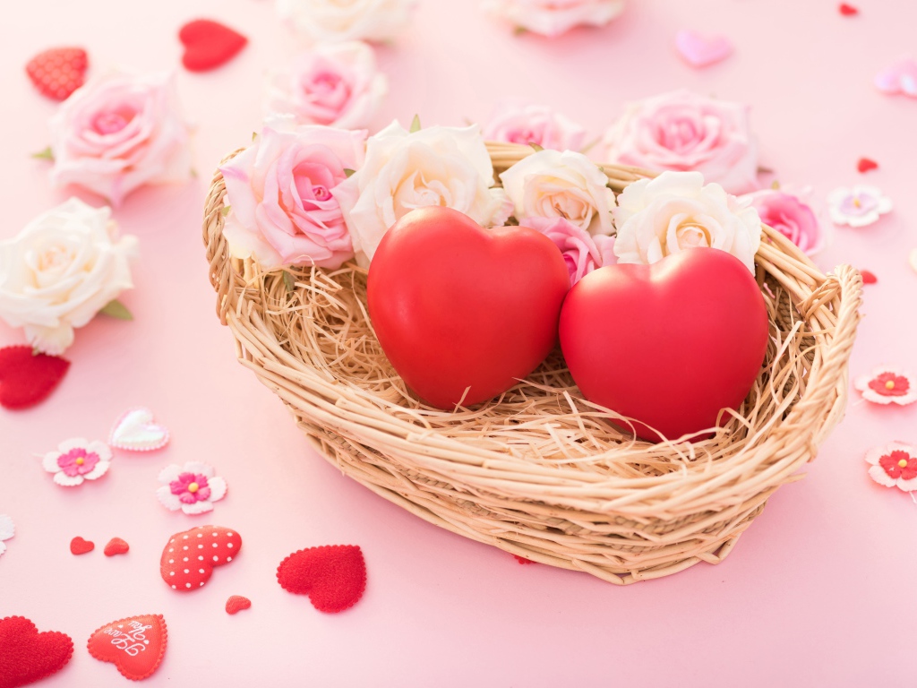 Два красных сердца лежат в корзинке с розами 