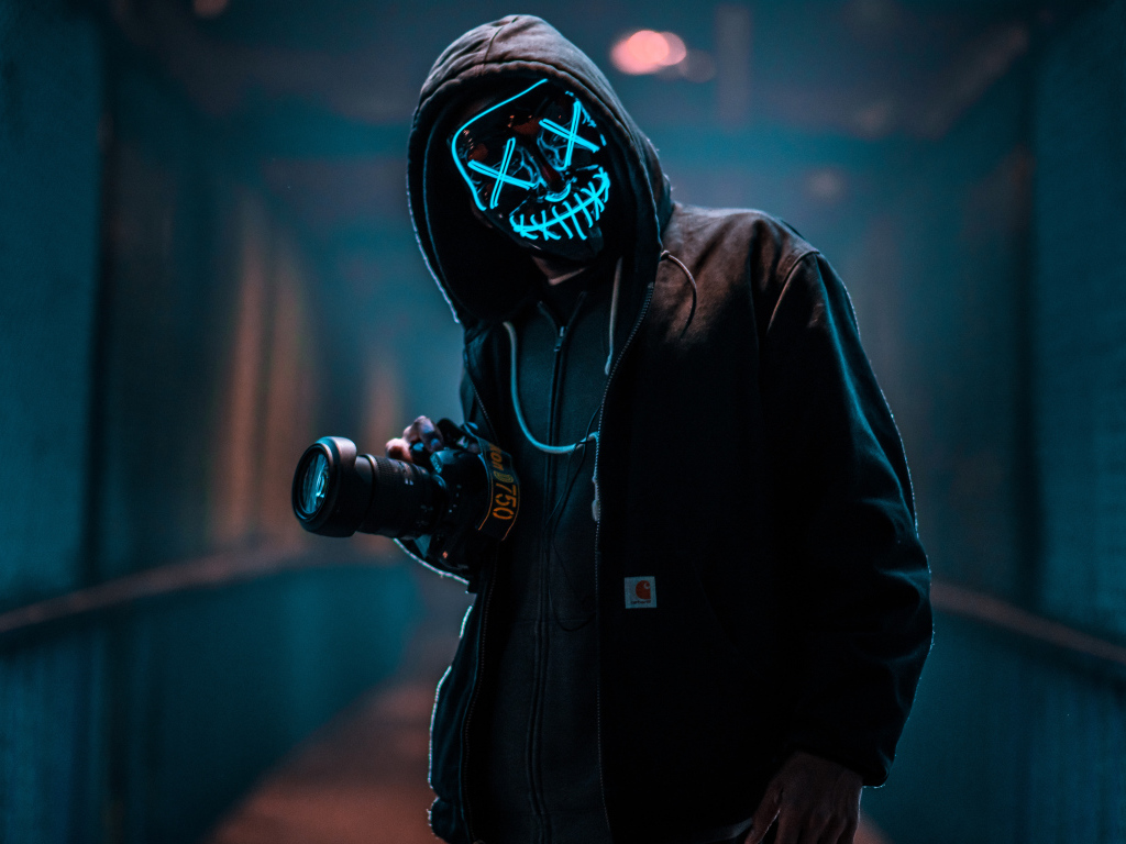 Парень в неоновой маске анонима с фотоаппаратом
