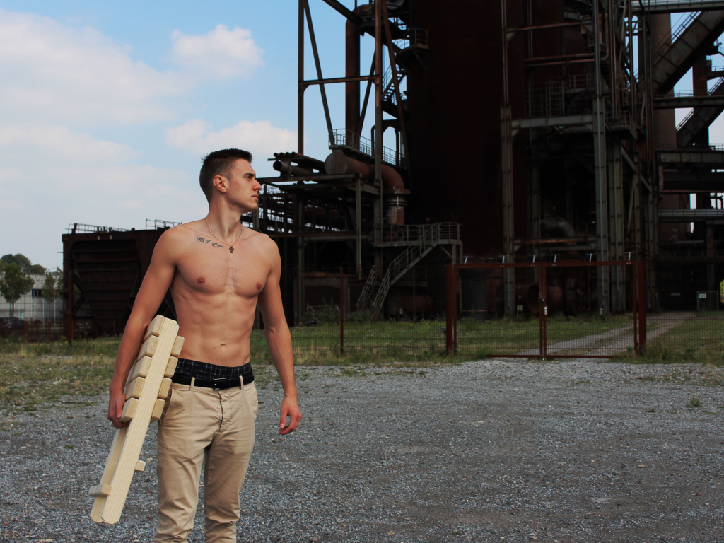 Красивый молодой парень стоит на фоне завода