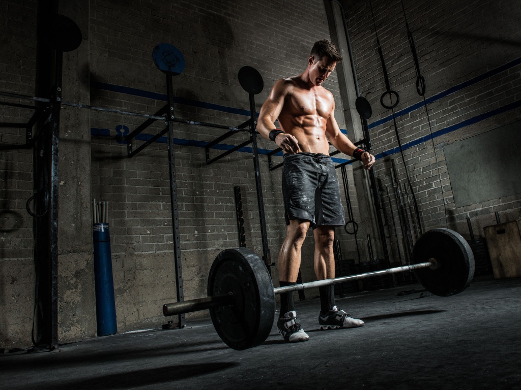 Мужчина спортсмен поднимает штангу в спортзале