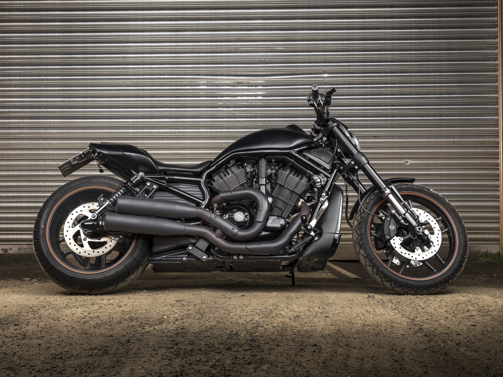 Черный тяжелый мотоцикл Harley-Davidson у гаража