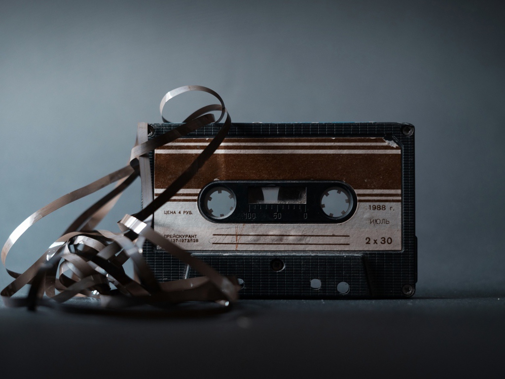 Старая кассета с вытянутой пленкой на сером фоне 