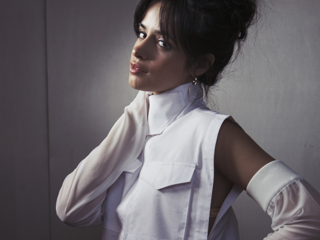 Молодая певица Камила Кабельо в белом костюме у стены