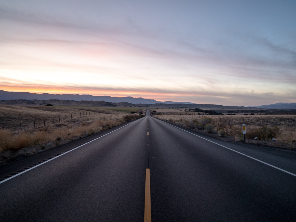 Асфальтная дорога уходит вдаль на фоне неба