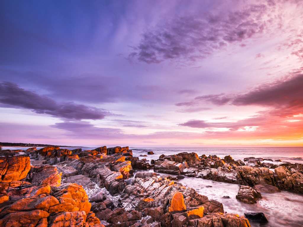 Каменный берег в море на закате солнца