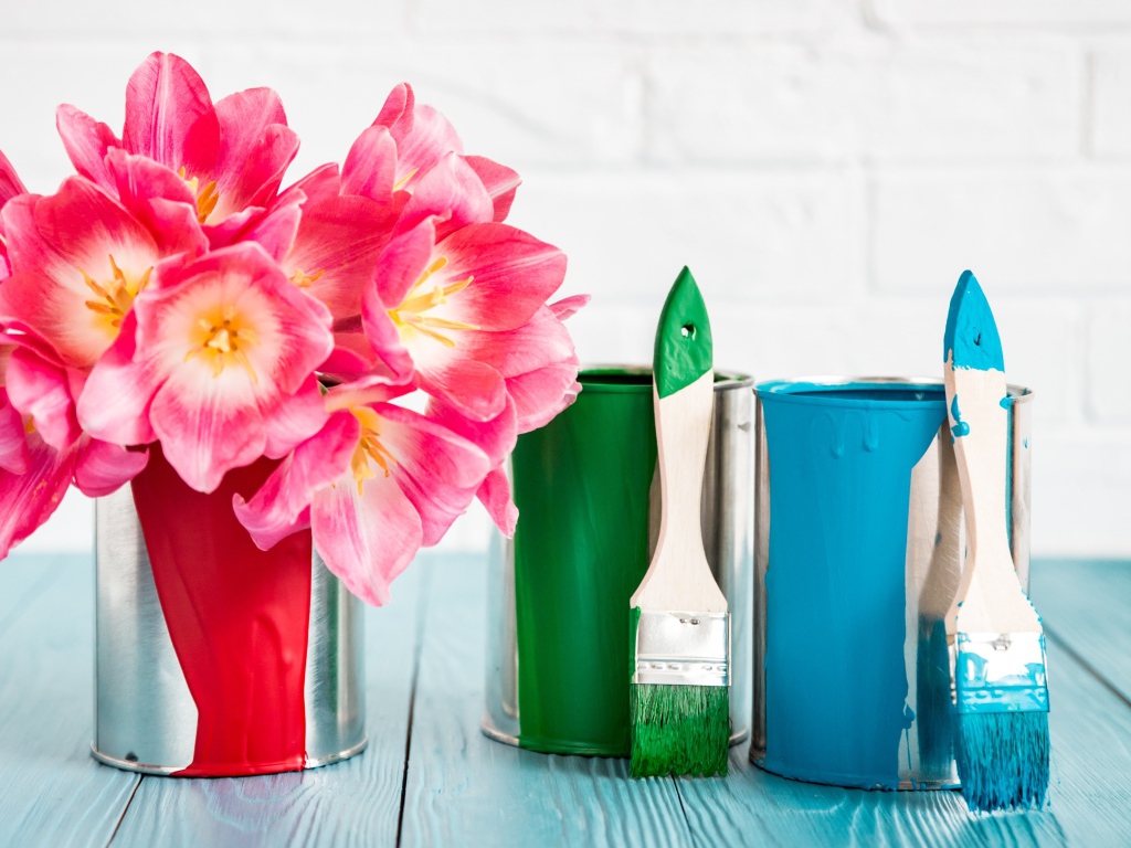 Букет розовых тюльпанов на столе с банками краски и кисточками