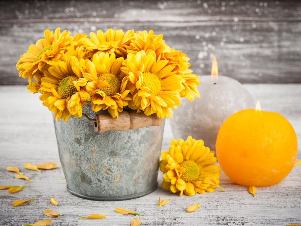 Букет желтых хризантем в ведерке на столе со свечами