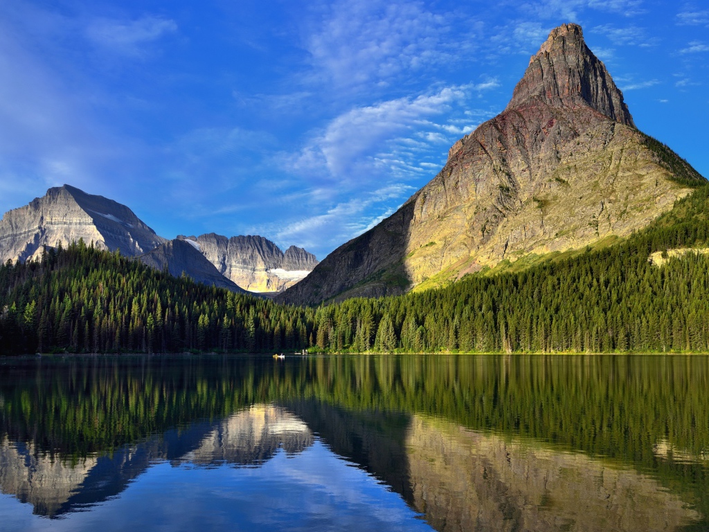 Каменные горы под голубым небом отражаются в воде