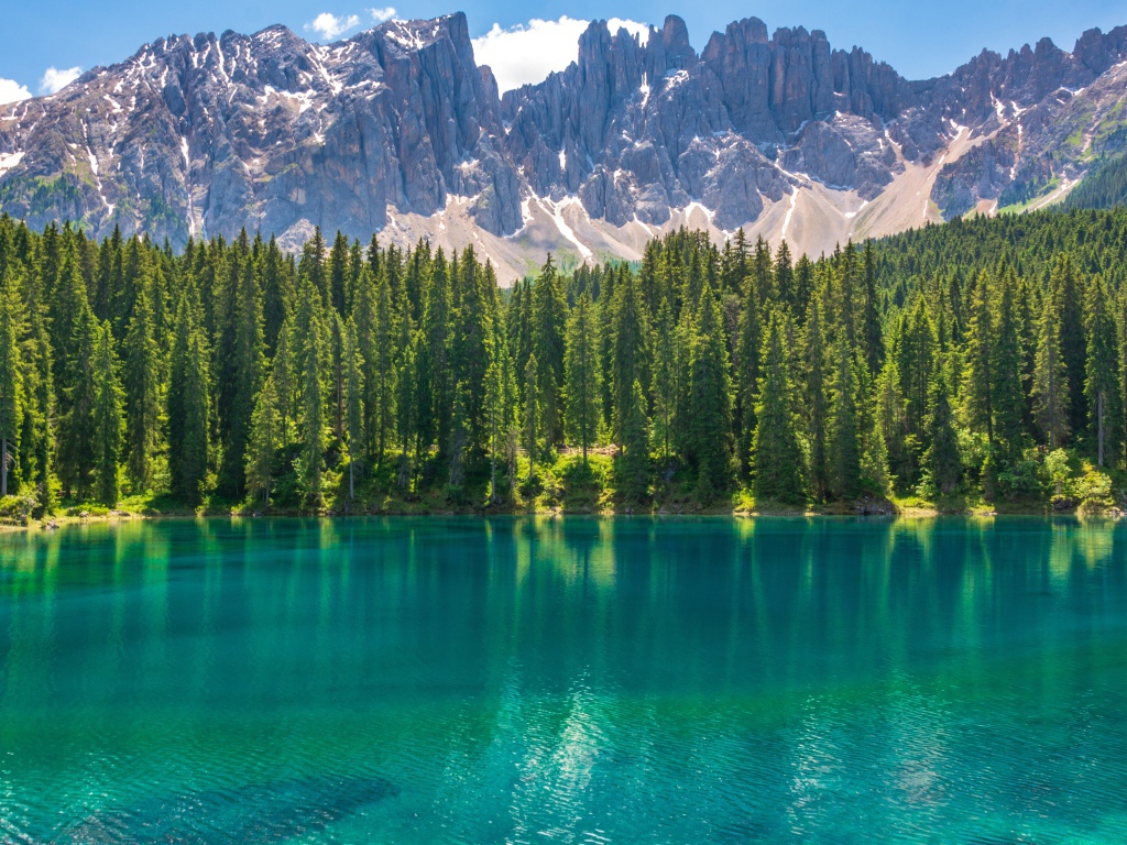 Красивое озеро с голубой водой у хвойного леса на фоне гор