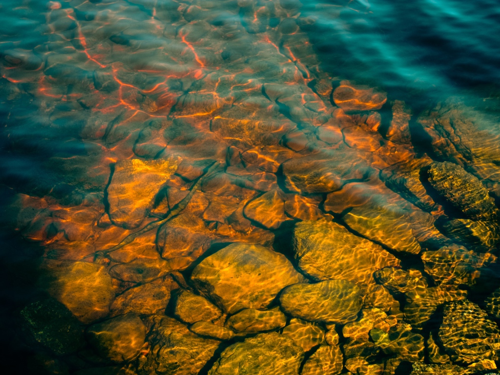 Камни на дне озера с чистой водой в лучах солнца