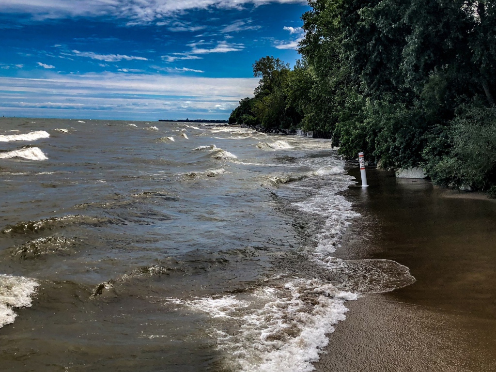 Морские волны омывают берег под голубым небом 