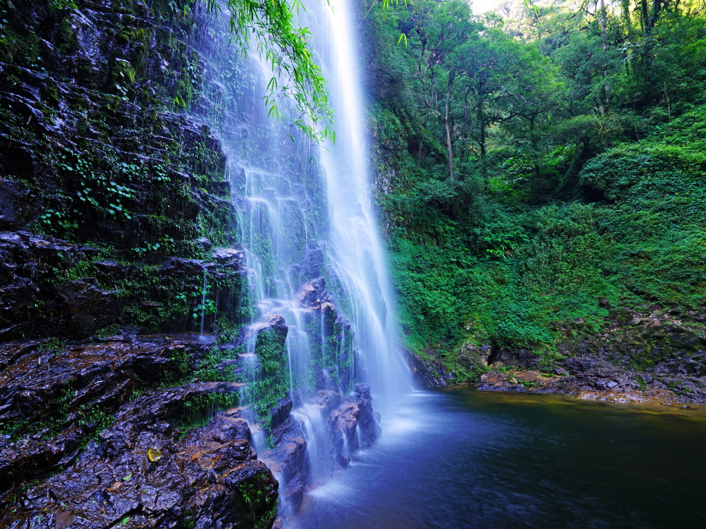 Быстрый водопад стекает по мокрым камням со скалы