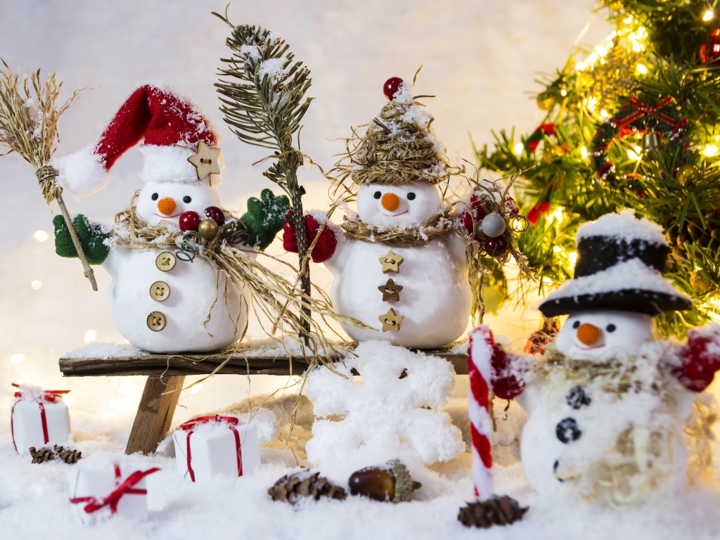 Три снеговика на снегу у искусственной елки на Новый год 