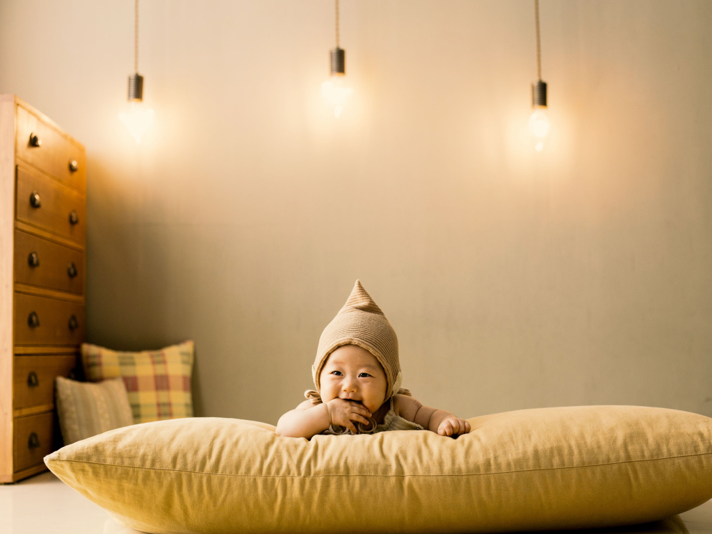 Маленький ребенок лежит на подушке под лампами