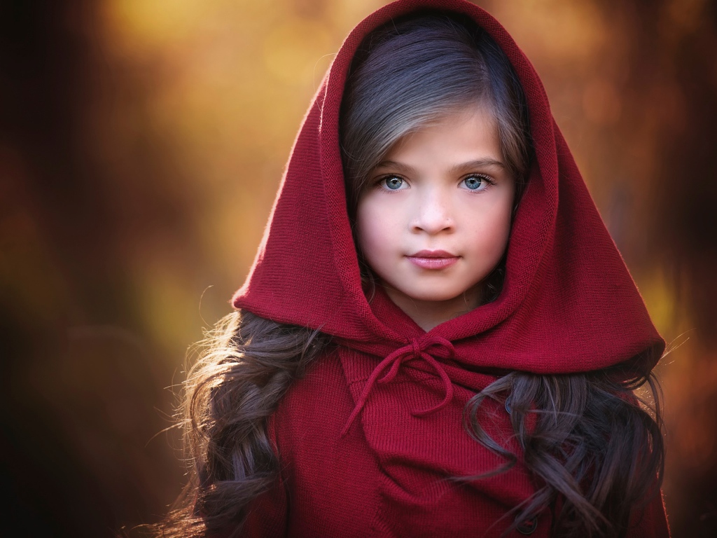 Маленькая красивая голубоглазая девочка с красным капюшоном на голове