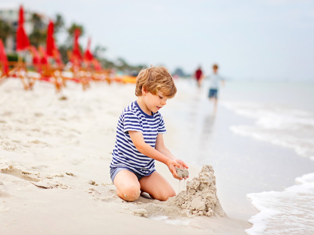 Little boy builds a sand castle on the beach