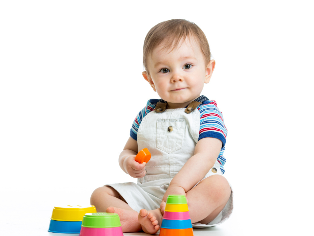 Маленький мальчик играет с пирамидкой на белом фоне