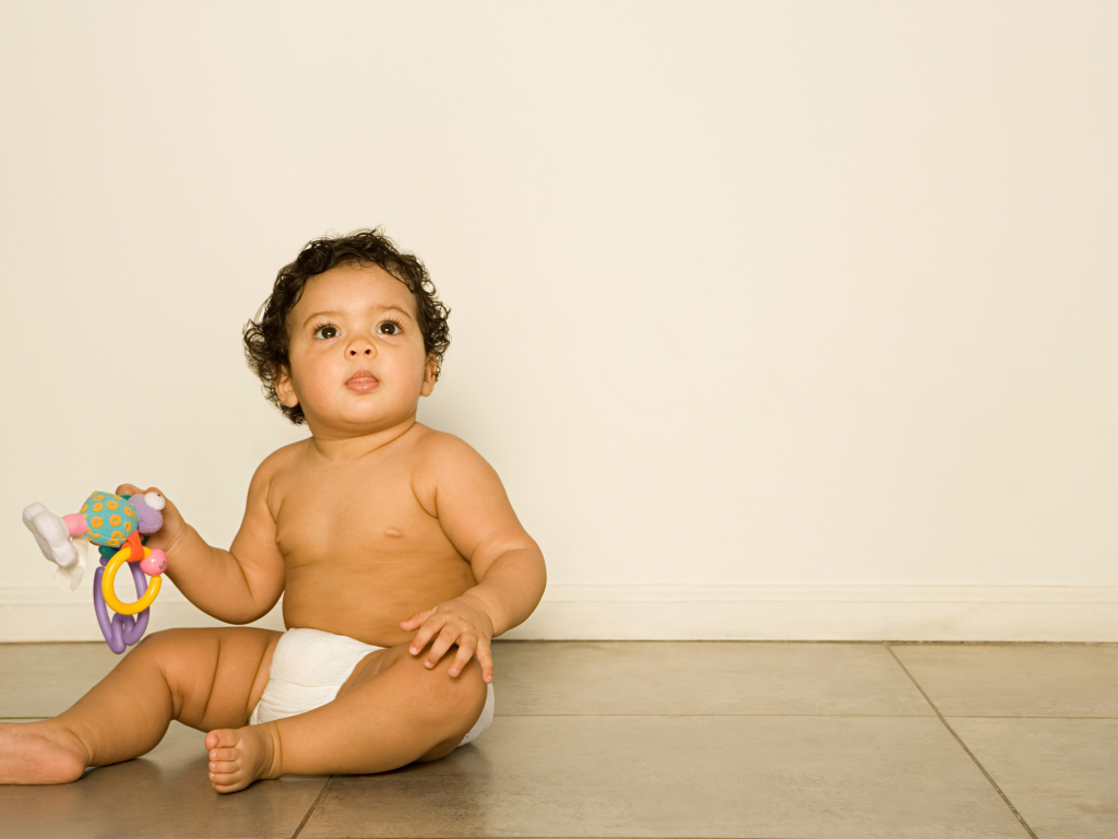 Маленький мальчик сидит на полу с игрушкой